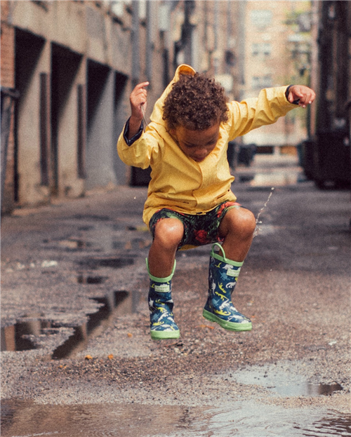 child jumping in a puddle
